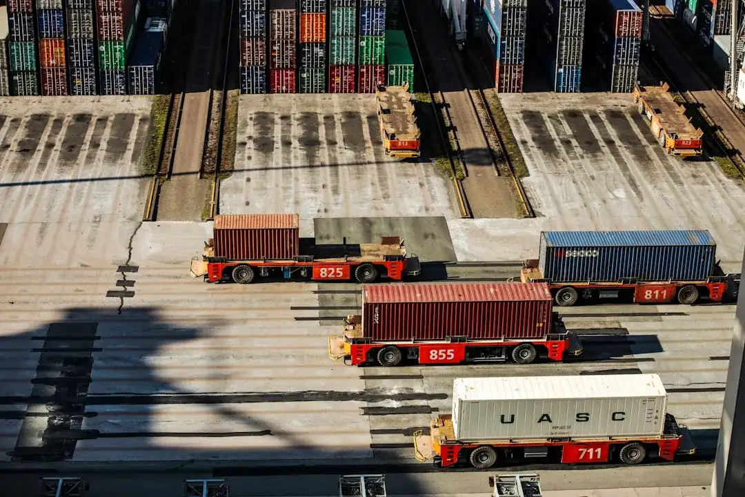 Automated trucks transport shipping containers in a port, with stacked colorful containers in the background.